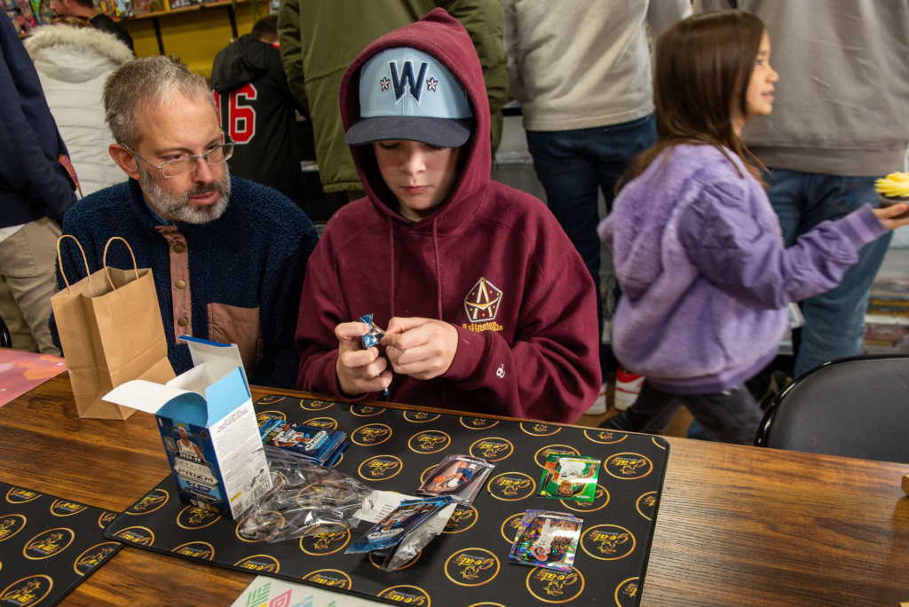 Collectors opening trading card pack at Goatz Sportz Cardz grand opening