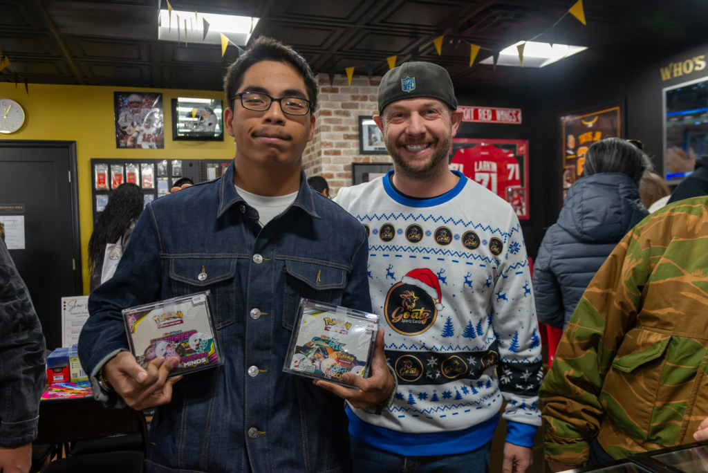 A customer showing off his Pokemon purchases with one of the owners