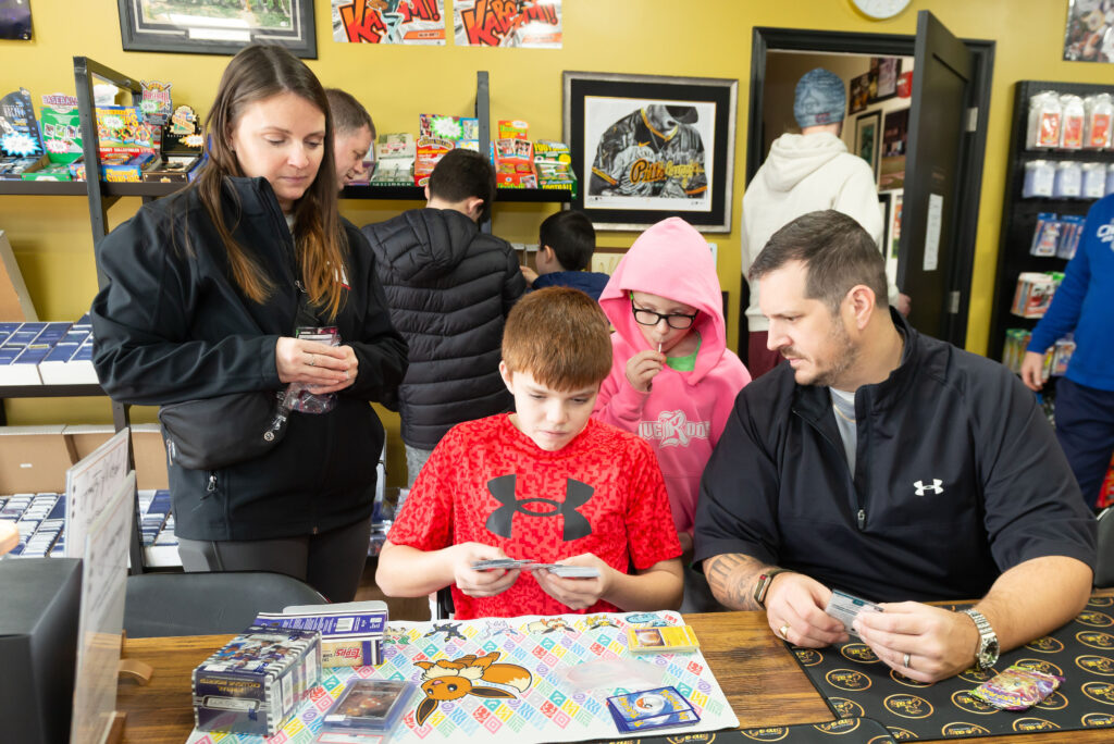 A family ripping boxes at Goatz Sportz Cardz grand opening
